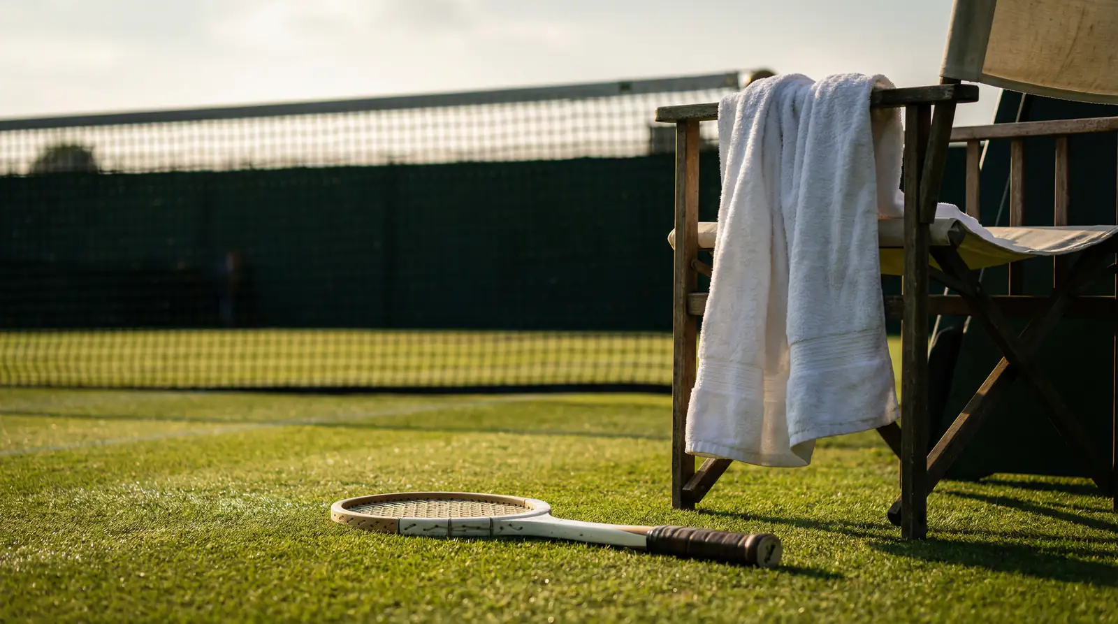 Leerer Stuhl auf dem Wimbledon-Rasenplatz mit zurückgelassenem Tennisschläger als Symbol für eine Spielaufgabe